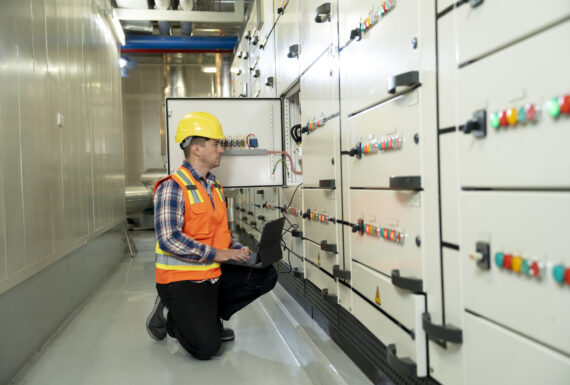 Electrical engineer monitoring system. Electrician Engineer working in electricity control room while examining of power distribution by mobile app on digital tablet.