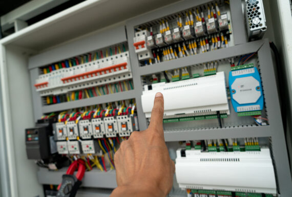 Human hand is flipping the power switch in the electrical control cabinet